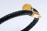 Close-up of the gold nail clasp and engraved EZELE emblem on the Wrap Soudage Black & Gold